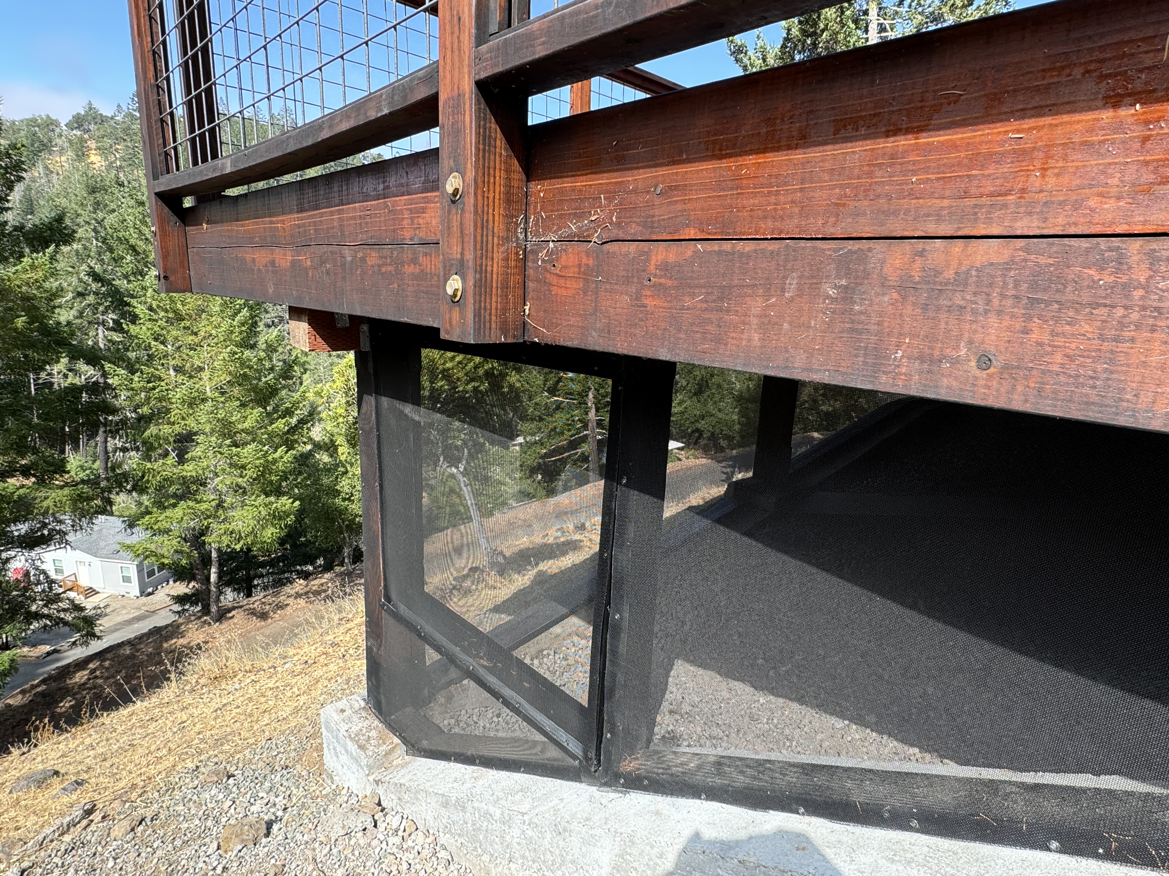 Ember-resistant mesh screening installed under a wood deck to prevent ignition from below