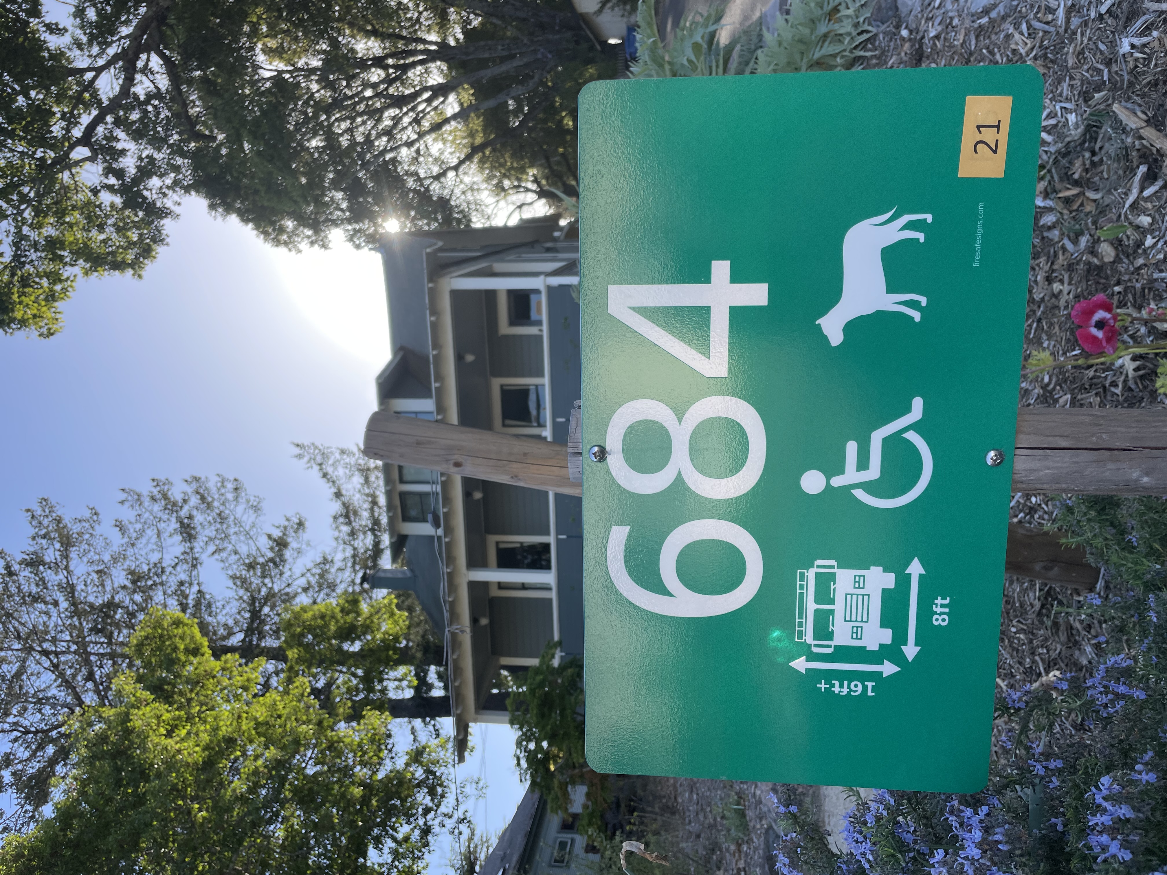 Green reflective rural address sign with horse, wheelchair, and fire truck clearance icons showing proper emergency access identification