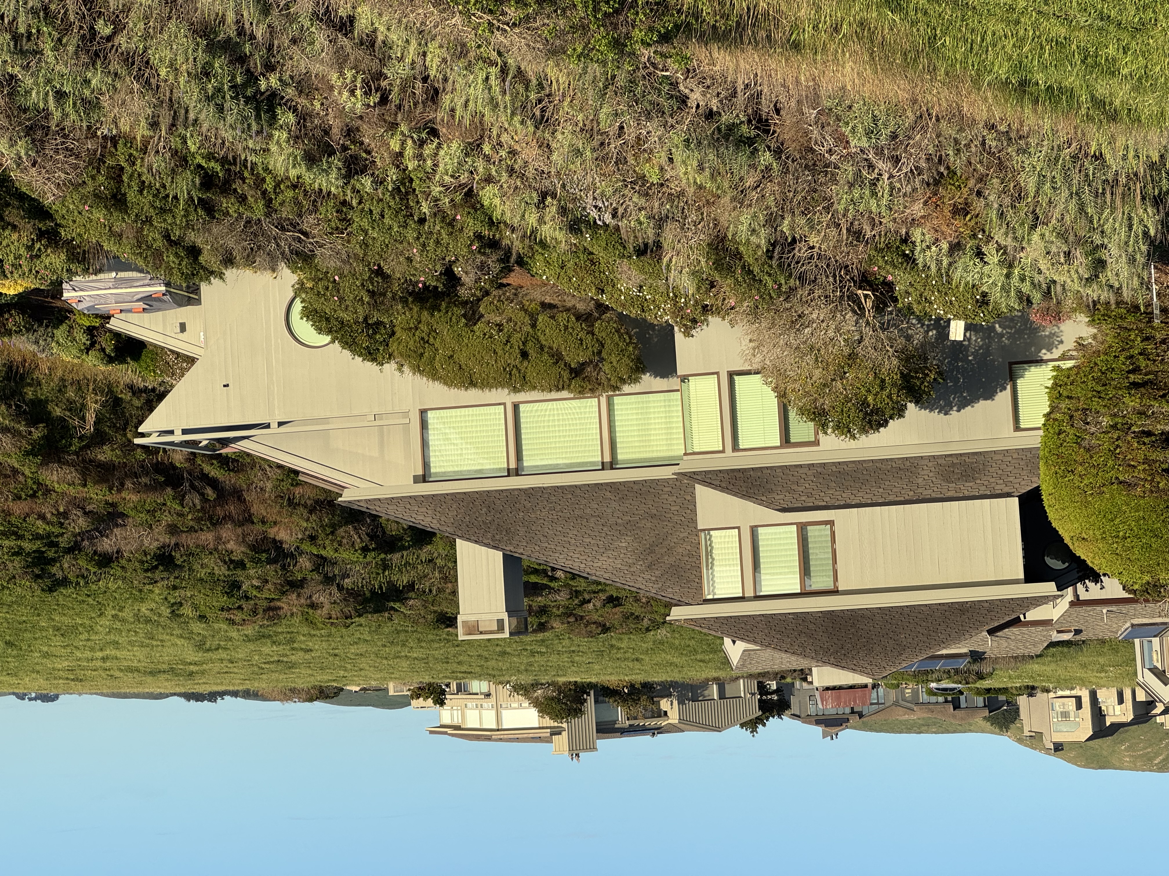 Residential property with landscaping growing against the structure, deck, and roofline, showing typical vegetation management needs