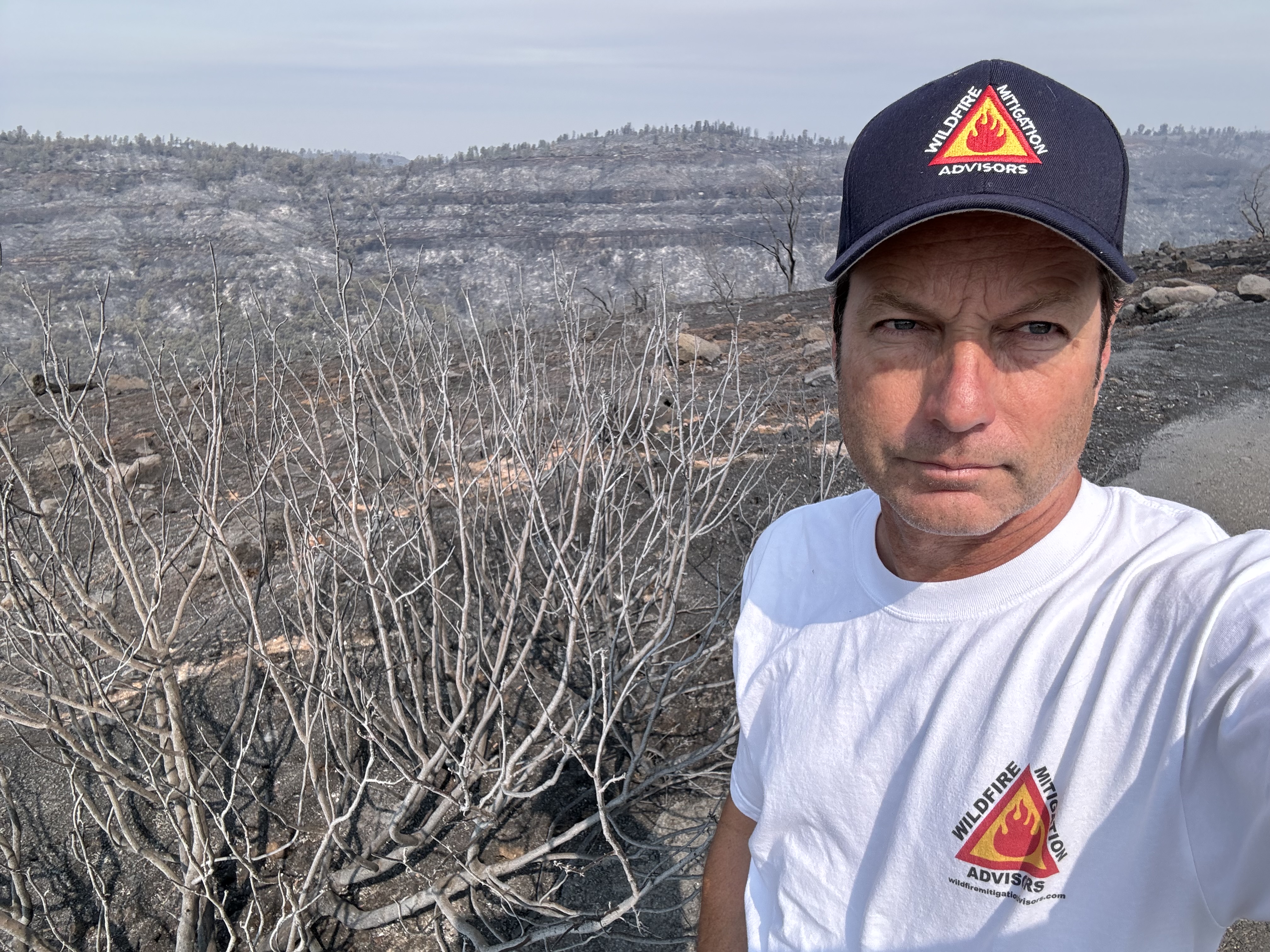 Stuart Mitchell surveying a burned hillside in WMA gear after a California wildfire
